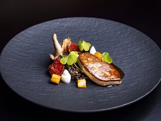 A skilfully prepared game dish with side dishes on a black plate. | © Graz Tourismus - Werner Krug