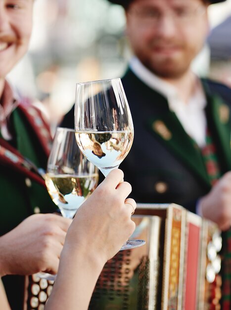 People holding wine glasses and an accordion. Festive atmosphere. | © BIO AUSTRIA Steiermark - Königshofer