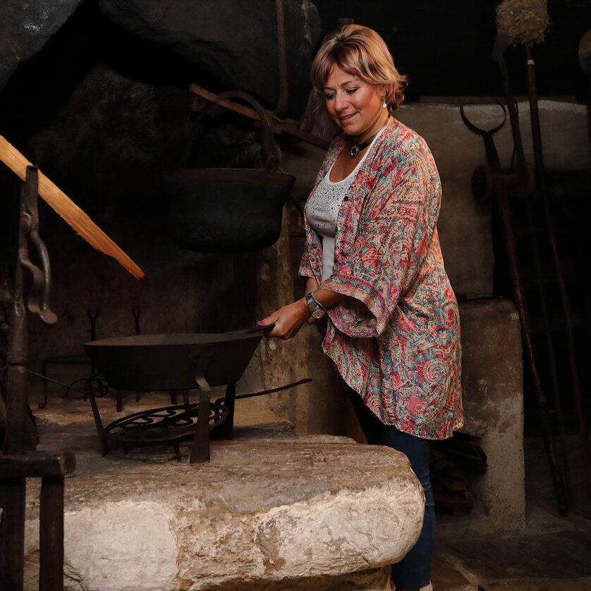 Genussreise im Volkskundemuseum I Sterzstunden | © Universalmuseum Joanneum - J. J. Kucek Frau steht an einem historischen Herd im Volkskundemuseum. | © Universalmuseum Joanneum - J. J. Kucek