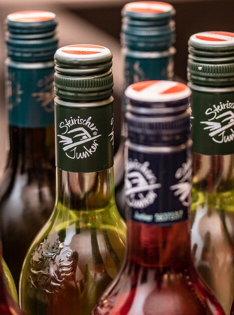 Bunte Flaschen "Steirischer Junker Wein" bei einer Präsentation. | © Fotokuchl