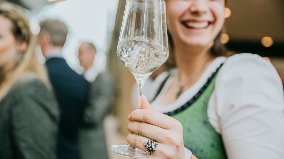 Eine fröhliche Frau mit einem Wein lächelt bei der Steirischen Junkerpräsentation. | © Wein Steiermark - Johanna Lamprecht