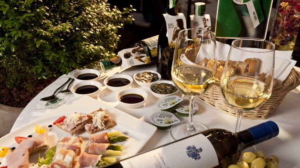 A table featuring various dishes, wines, and pumpkin seed oil. | © Graz Tourismus - Werner Krug