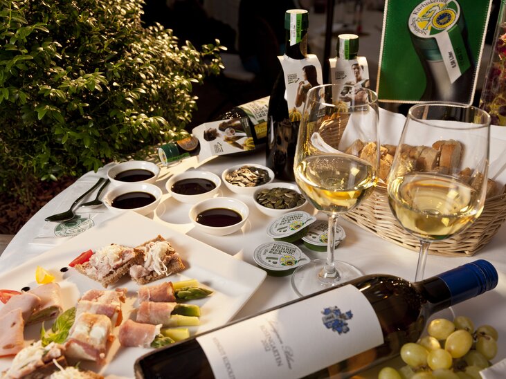 Ein Tisch mit verschiedenen Speisen, Weinen und Kürbiskernöl. | © Graz Tourismus - Werner Krug