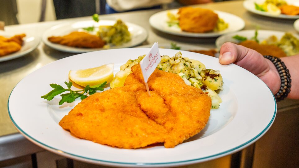 Ein Teller mit paniertem Hühnerfleisch, Zitrone und Kartoffelsalat als Beilage bei einem Kinder-Kochkurs in Graz. | © Graz Tourismus - Paul Stajan