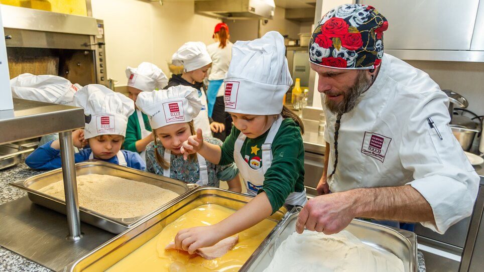Kinder beim Kochen in einer Küche, betreut von einem Koch. | © Graz Tourismus - Paul Stajan