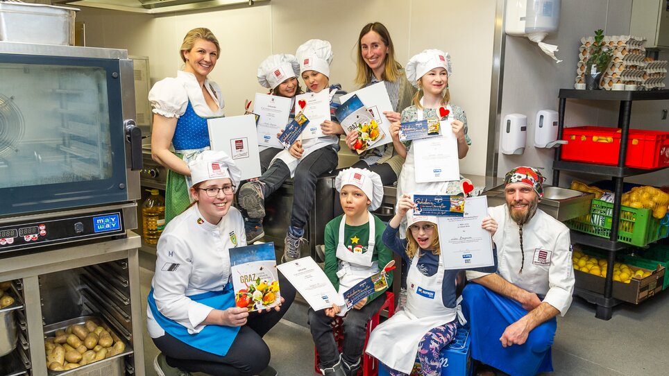 Kinder und Köche nach einem Kinderkochkurs in Graz - die Kinder halten Urkunden in den Händen. | © Graz Tourismus - Paul Stajan