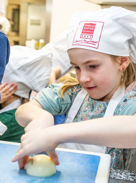 Mädchen bei einem Kochkurs, das Gemüse schneidet. | © Graz Tourismus - Paul Stajan