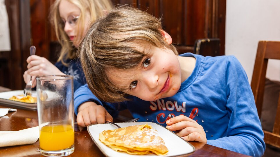 Ein Junge im Kinderkochkurs genießt Palatschinken. | © Graz Tourismus - Paul Stajan