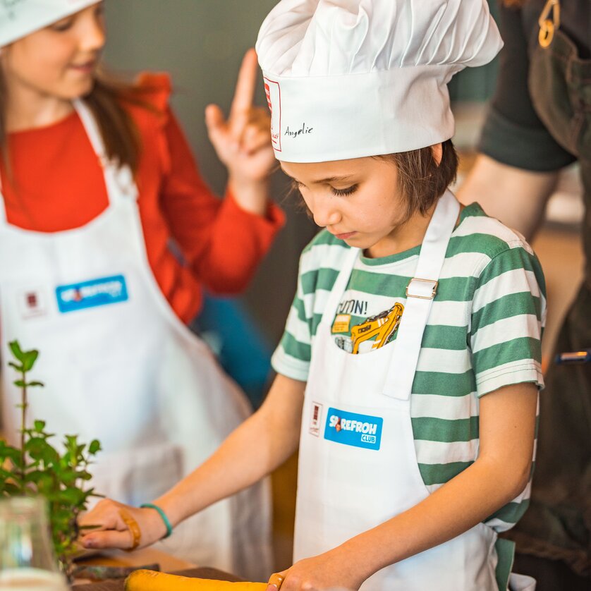 Kinder lernen Kochen in Graz mit Schürzen und Kochhauben. | © KHC - Bernhard Schindler