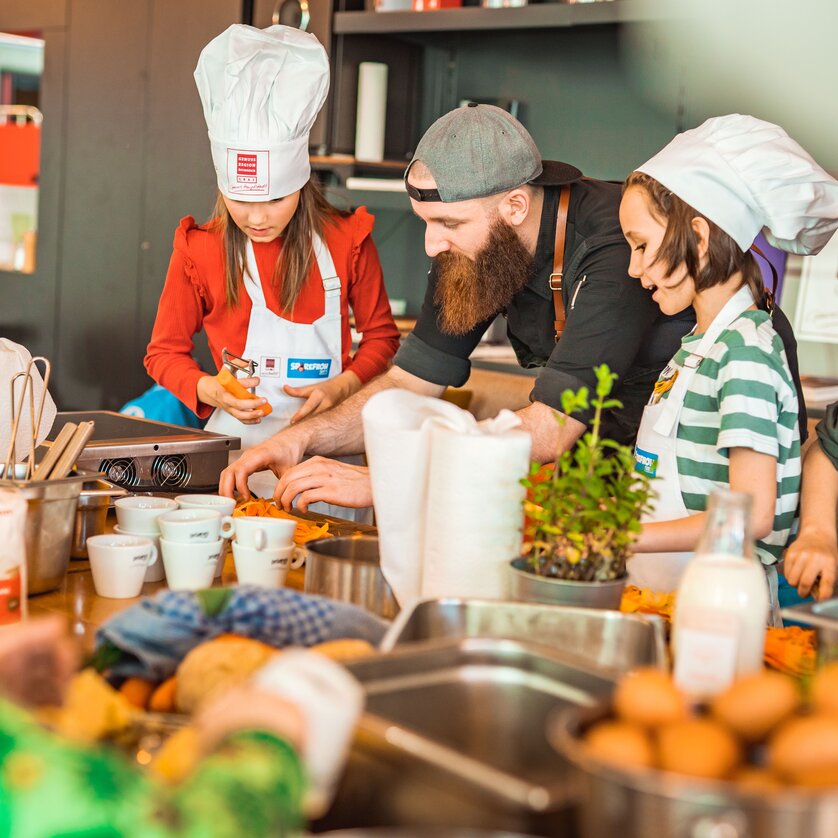 Kinderkochkurs in der GenussHauptstadt Graz | © KHC - Bernhard Schindler Kinder und ein Koch bereiten gemeinsam Gerichte in einer Kochschule vor. | © KHC - Bernhard Schindler