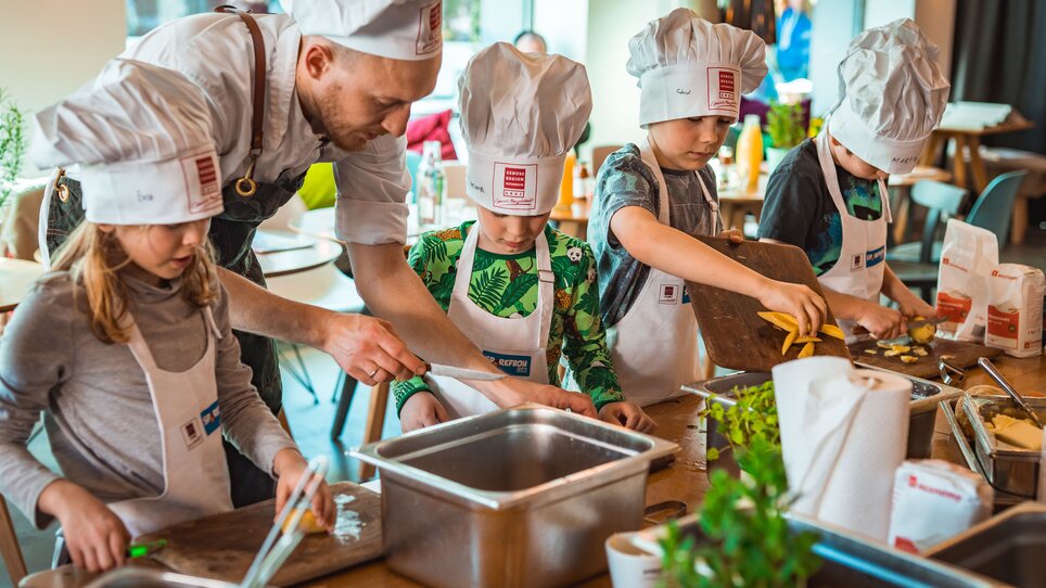 Kinder lernen beim Kochen in Graz, begleitet von einem Koch. | © KHC - Bernhard Schindler