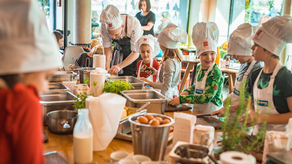 Kinder beim Kochen mit Schürzen und Kochmützen in Graz. | © KHC - Bernhard Schindler