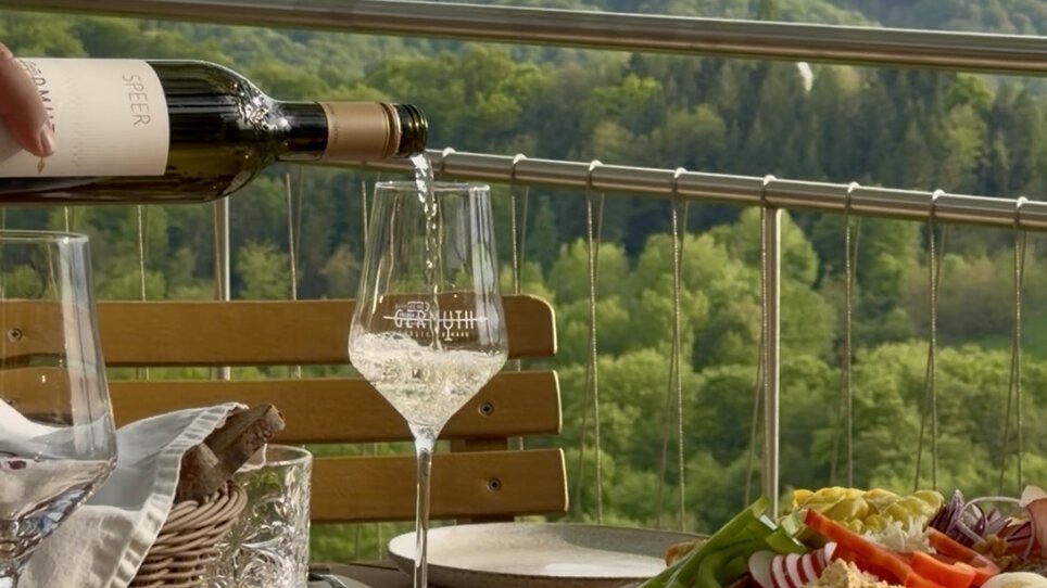 Un tavolo splendidamente apparecchiato con vino e vari piatti, affacciato sul paesaggio verde. | © Schanzlwirt
