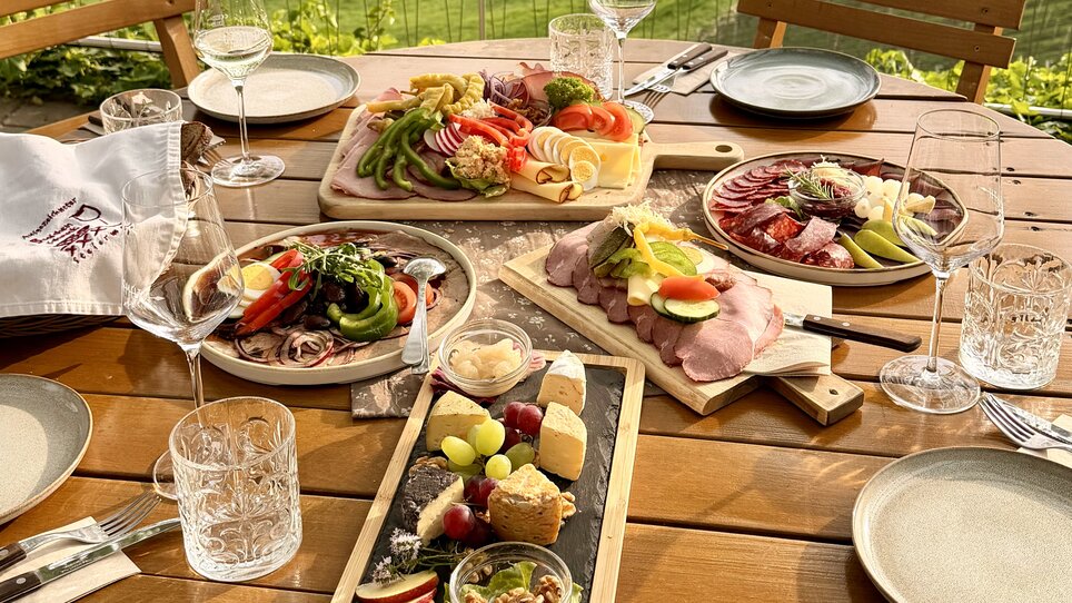 Piattaforme deliziose con formaggio, salumi e verdure fresche su un tavolo. | © Schanzlwirt