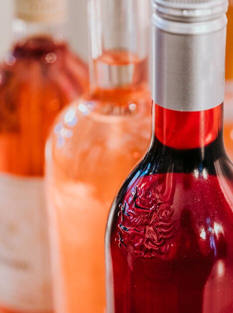 Close-up of three wine bottles with wine in different shades of rosé, from a delicate peachy pink to a strong light red. | © Johanna Lamprecht