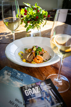 Ein Teller mit Pasta, Garnelen und Trüffeln, umgeben von Wein. | © Graz Tourismus - Werner Krug