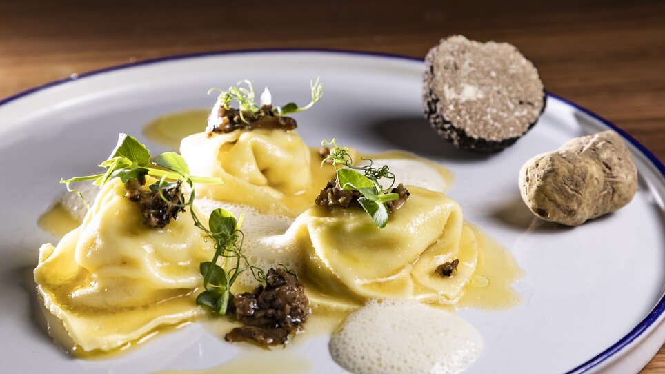 Tre ravioli ripieni di tartufo e salsa, guarniti con erbe. | © Graz Tourismus - Werner Krug