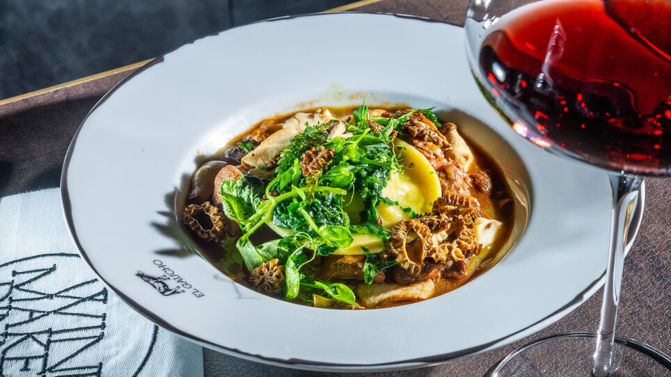 A plate of pasta, truffles, and fresh herbs, served with a glass of red wine. | © Paul Stajan