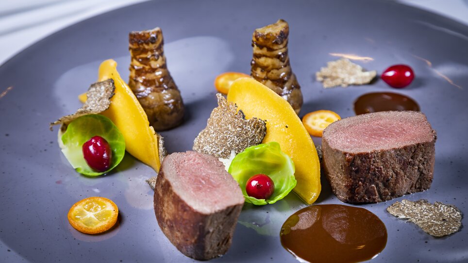 A dish featuring beef fillet, truffles, vegetables, and sauce on a gray plate. | © Graz Tourismus - Werner Krug