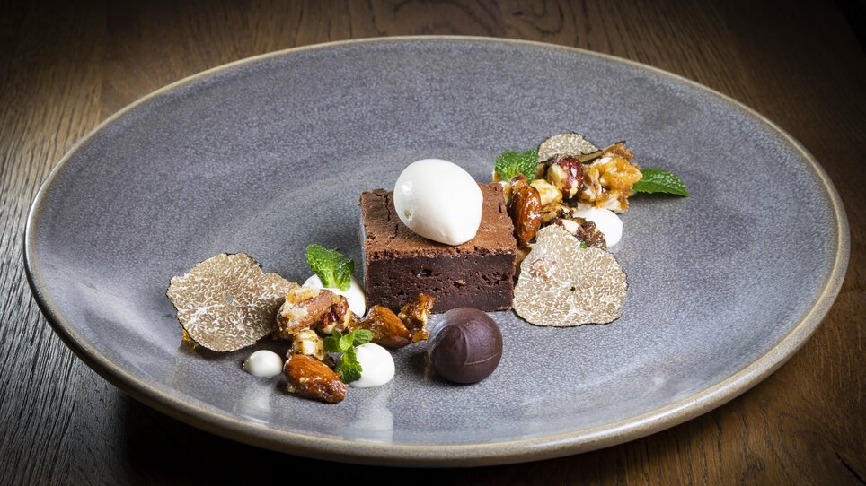 Un dessert lussuoso con brownie, tartufi e gelato, presentato su un piatto grigio. | © Graz Tourismus - Werner Krug