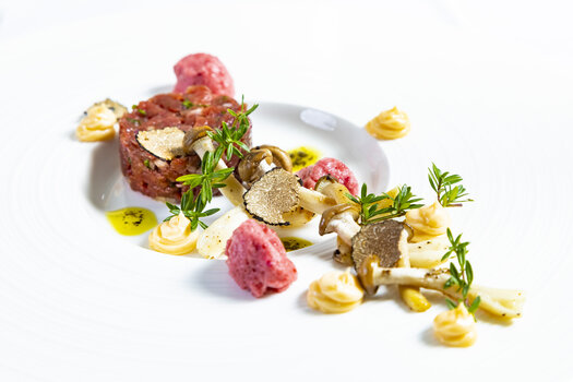 An artistic dish featuring beef tartare, truffles, and mushrooms on a plate. | © Graz Tourismus - Werner Krug