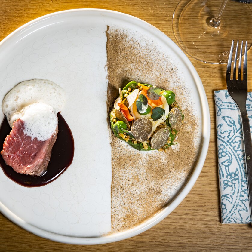 Ein kunstvoll angerichteter Teller mit Fleisch, einer Soße und Gemüse. | © Graz Tourismus - Werner Krug