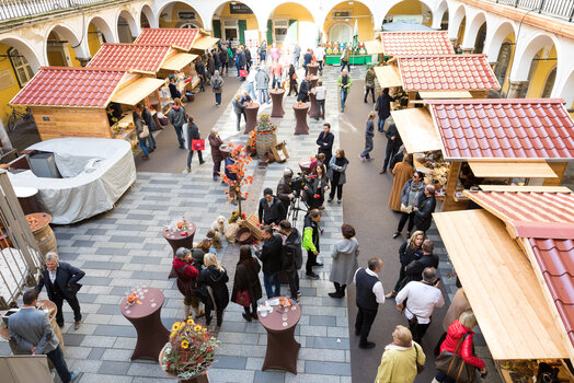 Busy truffle market in the Paradeishof with vendors and buyers, wooden stalls, and decorative elements. | © Graz Tourismus - Harry Schiffer