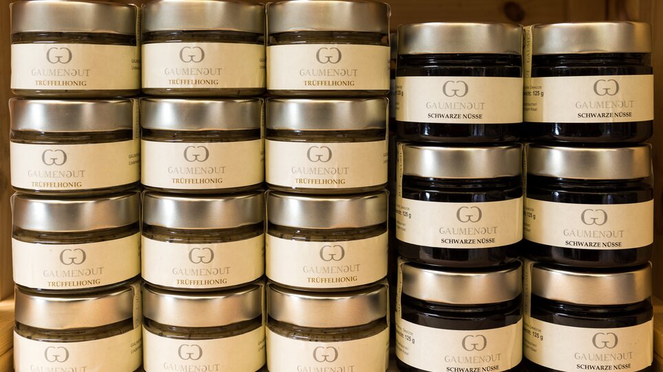 A variety of jars filled with truffle honey and black nuts on shelves. | © Graz Tourismus Harry Schiffer