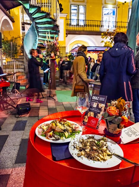 A beautifully arranged table with truffle dishes, glasses, and floral decorations. Visitors enjoy the festival in the Paradeishof. | © Graz Tourismus - Werner Krug