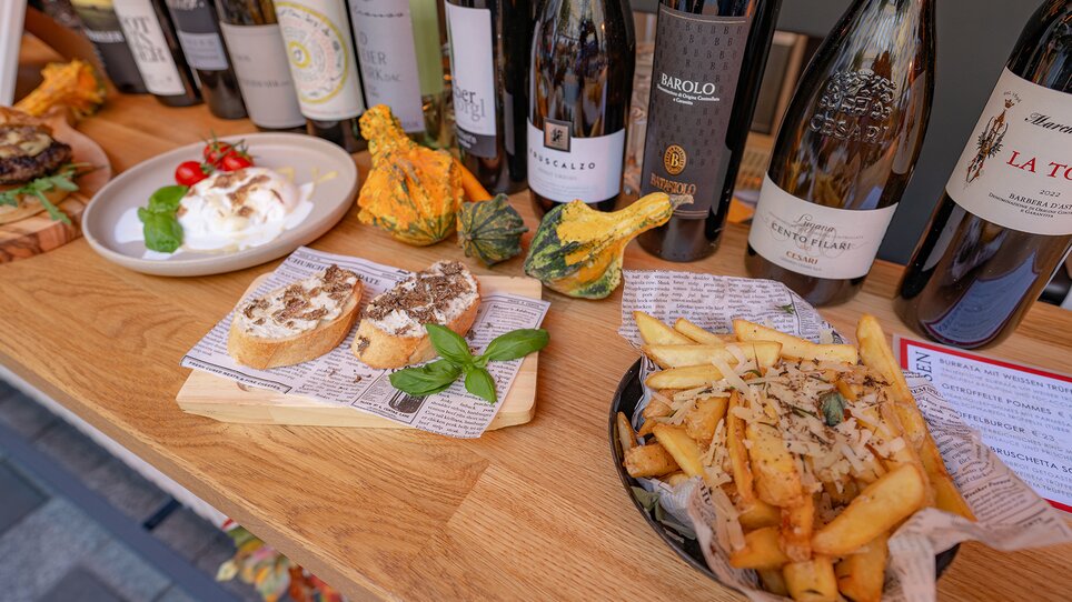 Eine Auswahl an Weinen, Trüffelgerichten und Beilagen auf einem Holztisch. | © 5komma5sinne - Rene Strasser