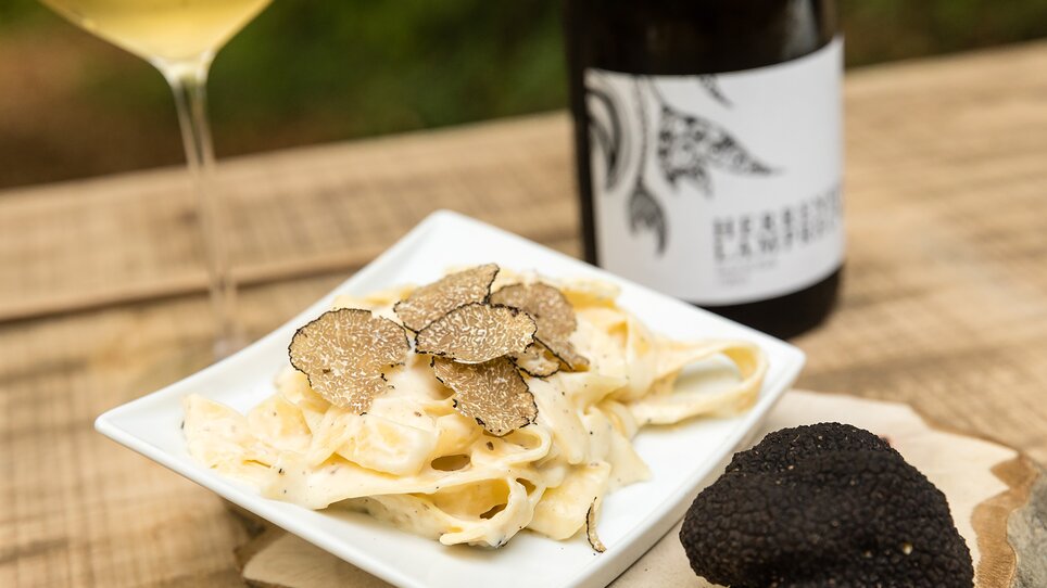 Ein Teller Pasta mit Trüffeln, Wein im Hintergrund. | © Graz Tourismus - Harry Schiffer