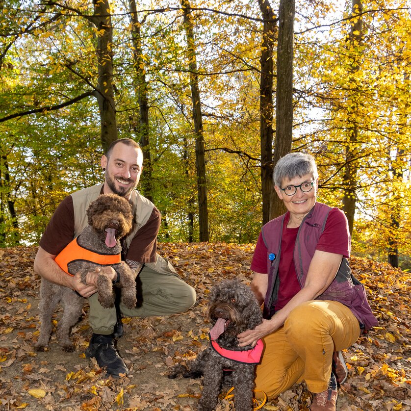 Zwei Personen mit braunen Hunden im Herbstwald. | © Graz Tourismus - Harry Schiffer