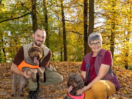 Zwei Personen mit braunen Hunden im Herbstwald. | © Graz Tourismus - Harry Schiffer