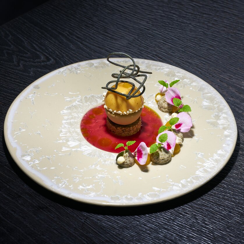 Ein dekoriertes Dessert mit Sorbet und Blüten auf einem Teller. | © Bastian Knapp