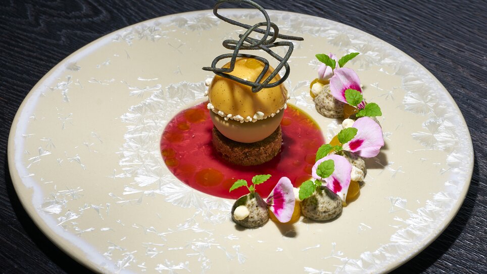 Ein dekoriertes Dessert mit Sorbet und Blüten auf einem Teller. | © Bastian Knapp