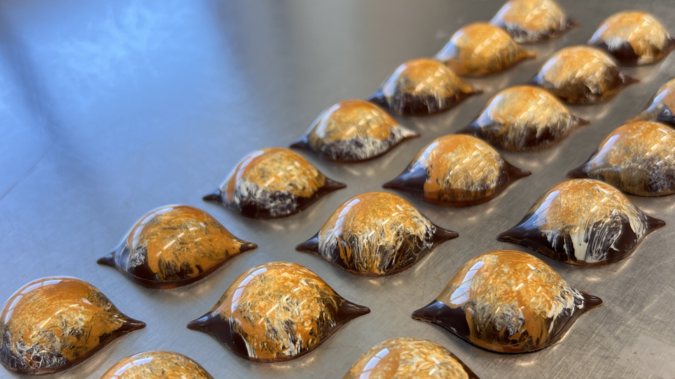 Kleine, kunstvoll geformte Pralinen auf einem Metalltisch. | © Jaimy Reisinger