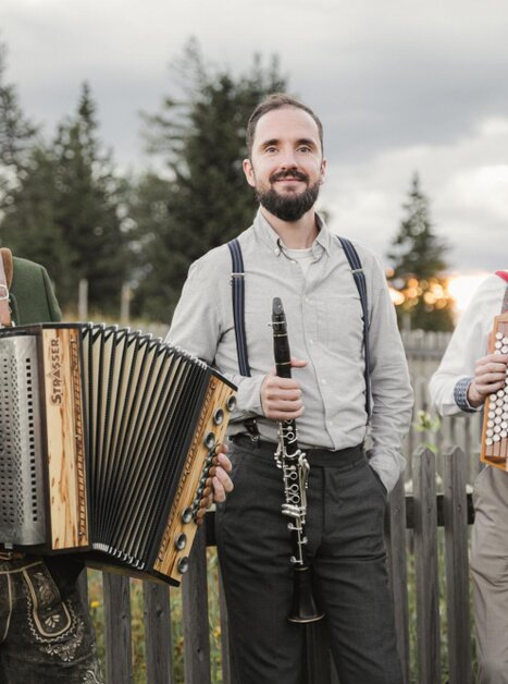 Tre musicisti con fisarmoniche e un clarinetto posano all'aperto.