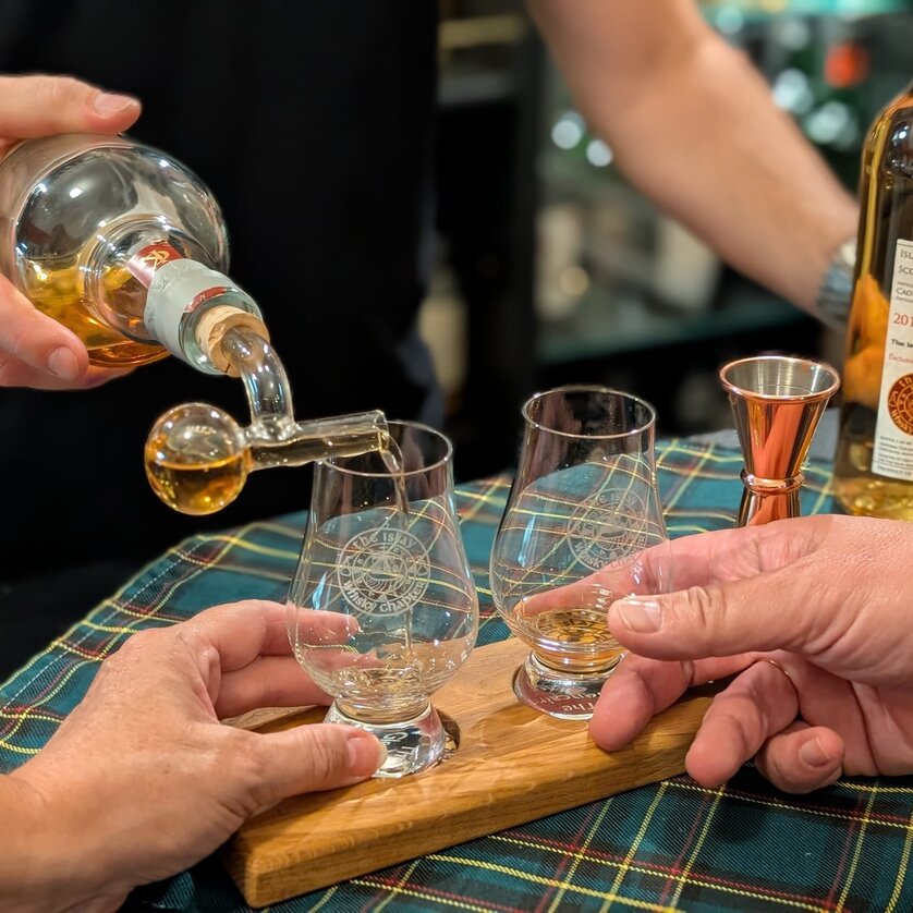 Two glasses are being filled with whiskey while two hands are ready. | © The Islay Whisky Chapter Austria