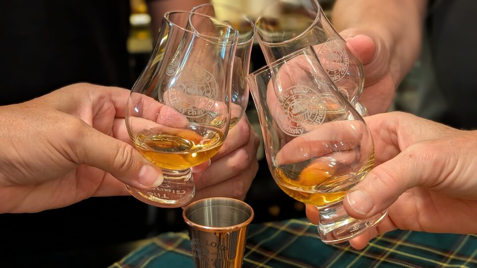 Four hands lifting whisky glasses for a toast. | © The Islay Whisky Chapter Austria