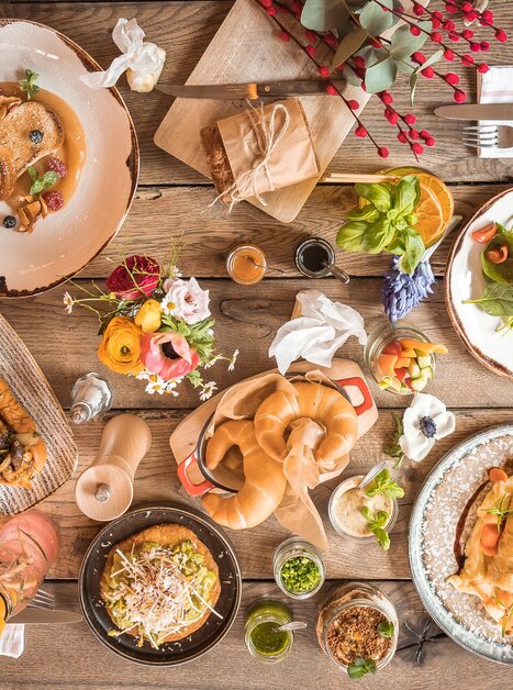 Vielfältige Gerichte, Getränke und Blumenarrangements auf einem Holztisch. | © Kunsthaus Graz