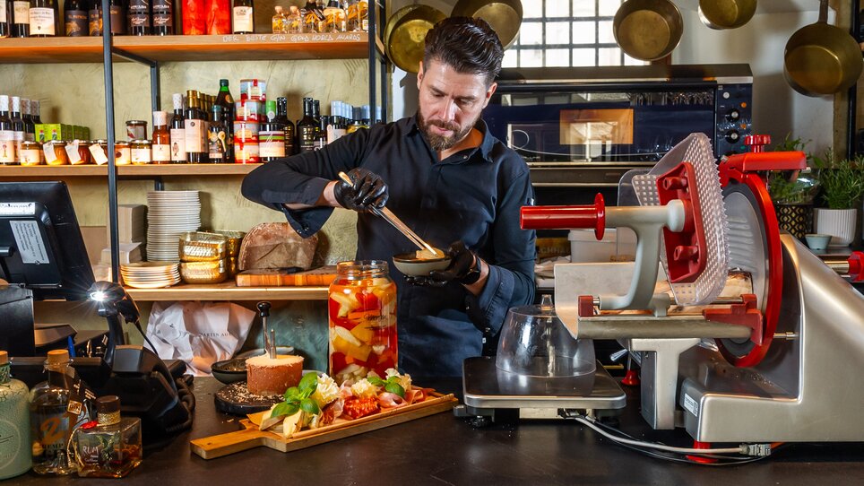 Ein Koch bereitet ein Gericht mit frischen Zutaten an einer Theke zu. | © Paul Stajan