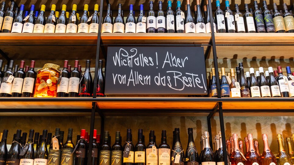 Weinregal mit verschiedenen Flaschen und handgeschriebenem Schild. | © Paul Stajan