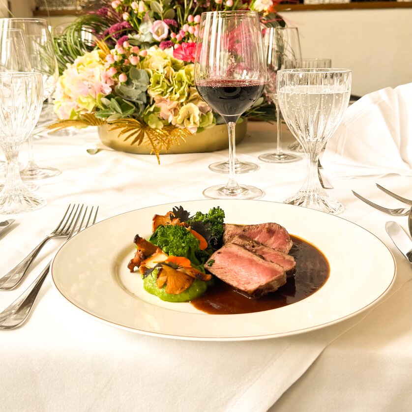 Piatto gourmet su un tavolo splendidamente apparecchiato con fiori. | © Grand Hotel Wiesler