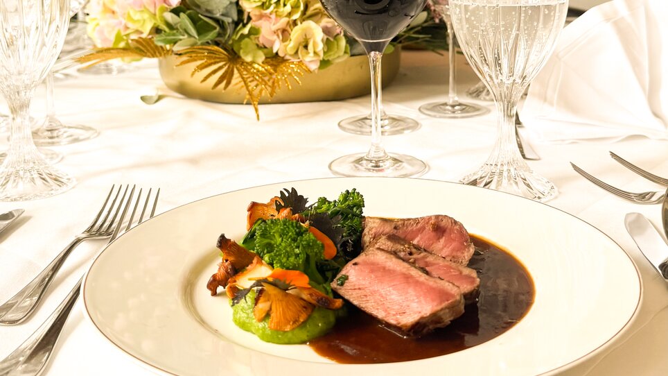 Piatto gourmet su un tavolo splendidamente apparecchiato con fiori. | © Grand Hotel Wiesler