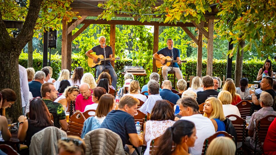 Two musicians playing acoustic guitars for an audience in a restaurant. | © Werner Krug