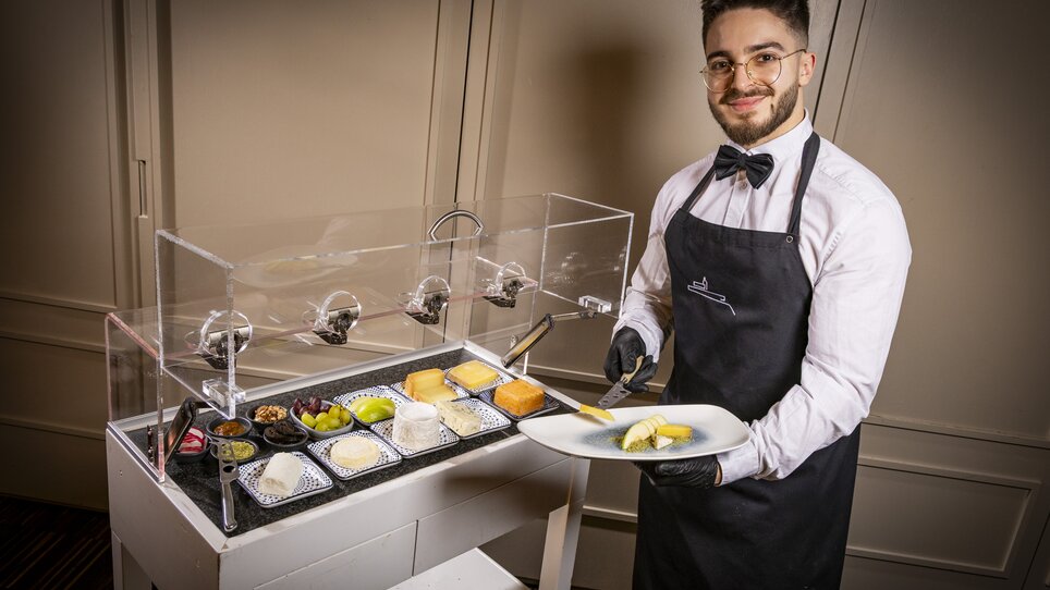 Marcel Müller serviert Speisen an einem Essenswagen.
