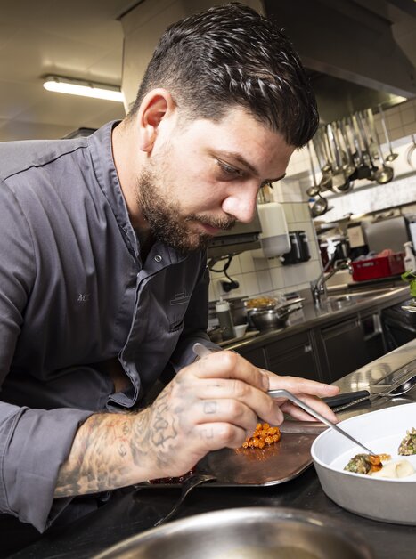 A chef garnishing a plate of food in a modern kitchen. | © Werner Krug