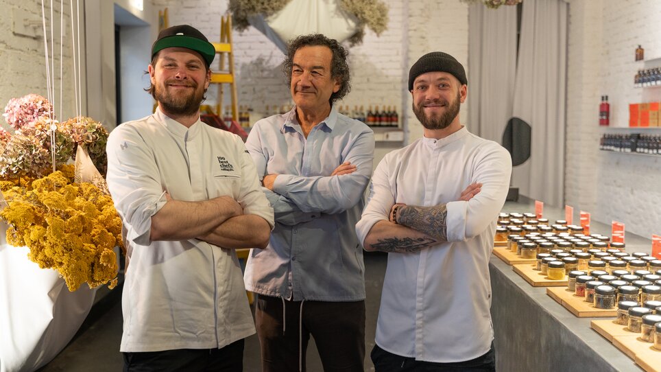 Drei Männer in Kochkleidung posieren in einem stilvollen Kochumfeld. | © Michael Kink