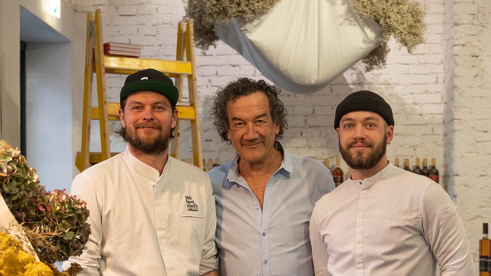 Drei Männer in Kochjacken posieren in einem Restaurant. | © Michael Kink