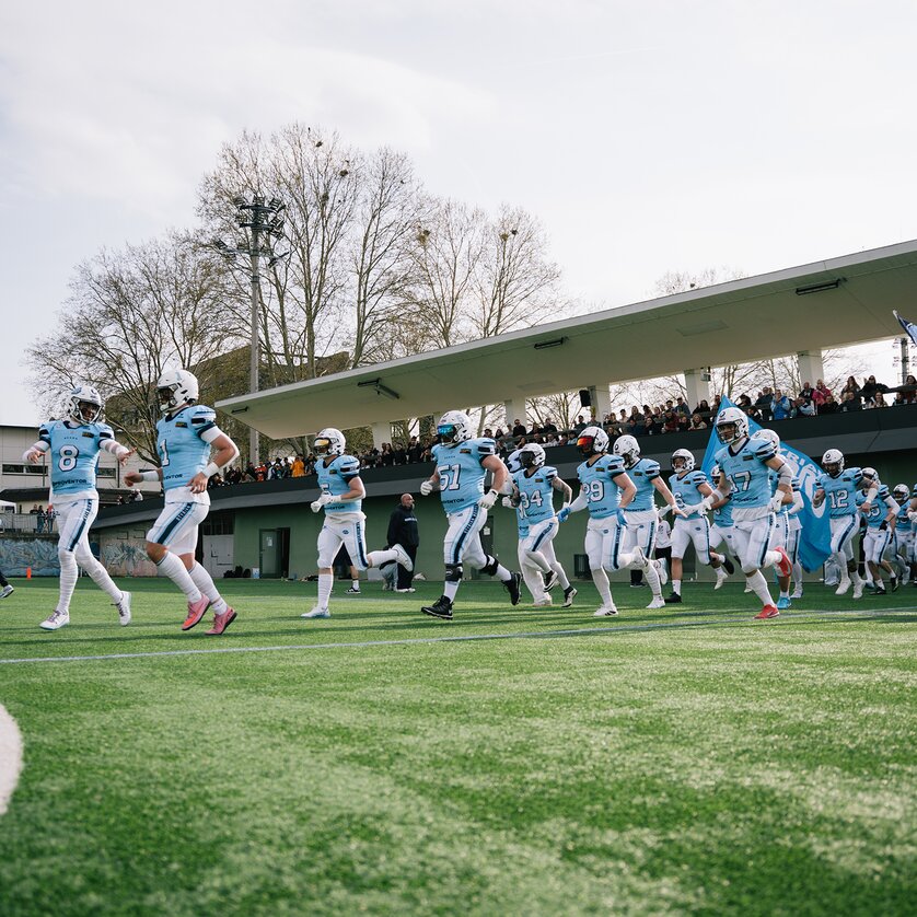 A group of football players run onto the field, with spectators in the stands. | © Georg Obetzhofer